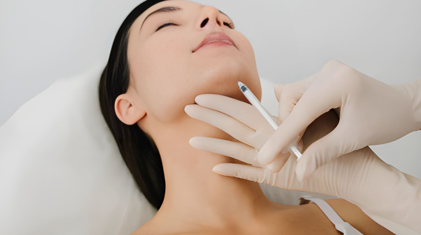 A woman enjoys a facial treatment, lying on a treatment bed with soothing lighting around her.