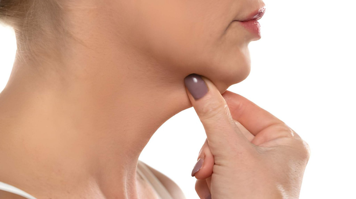 A woman with a thoughtful demeanor touches her chin to her neck in a reflective pose.