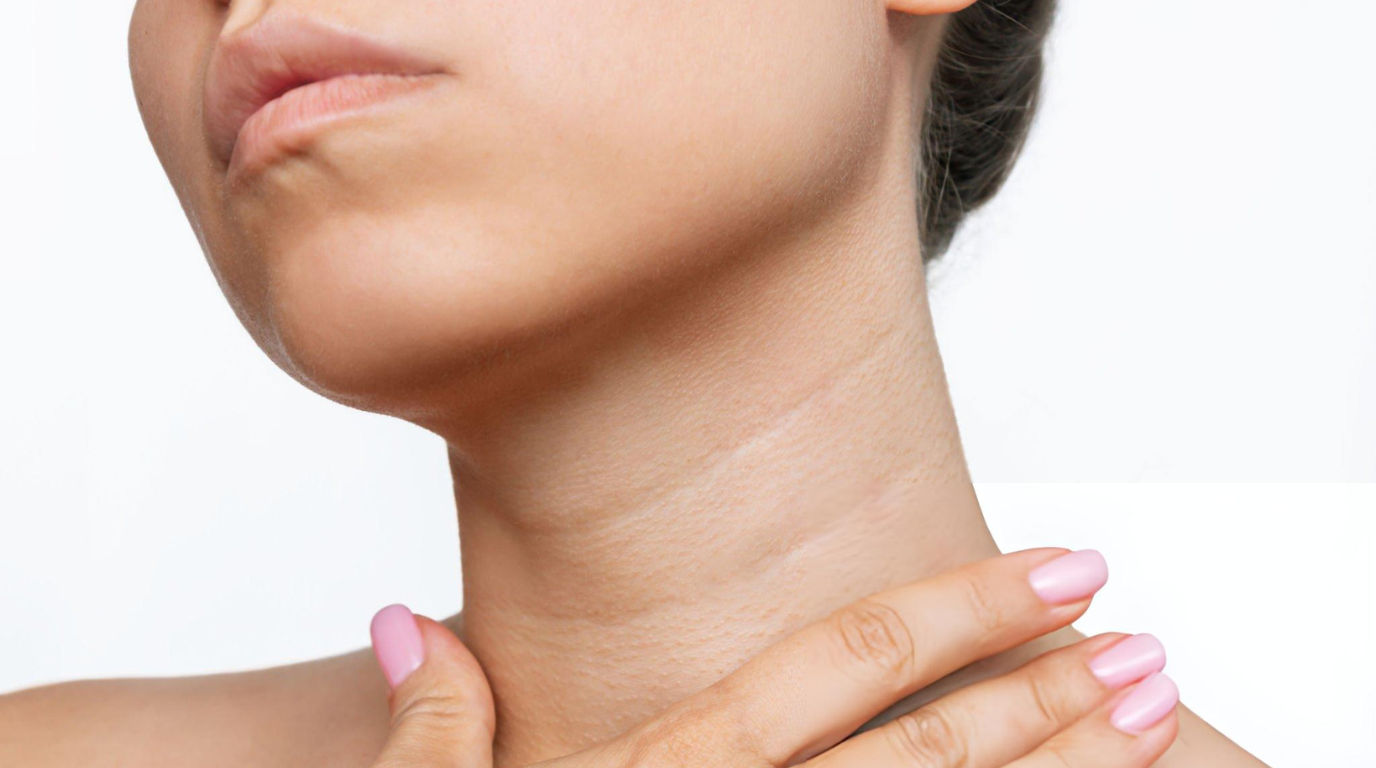 A woman features a prominent neck tattoo and vibrant pink nails, reflecting her bold fashion choices.